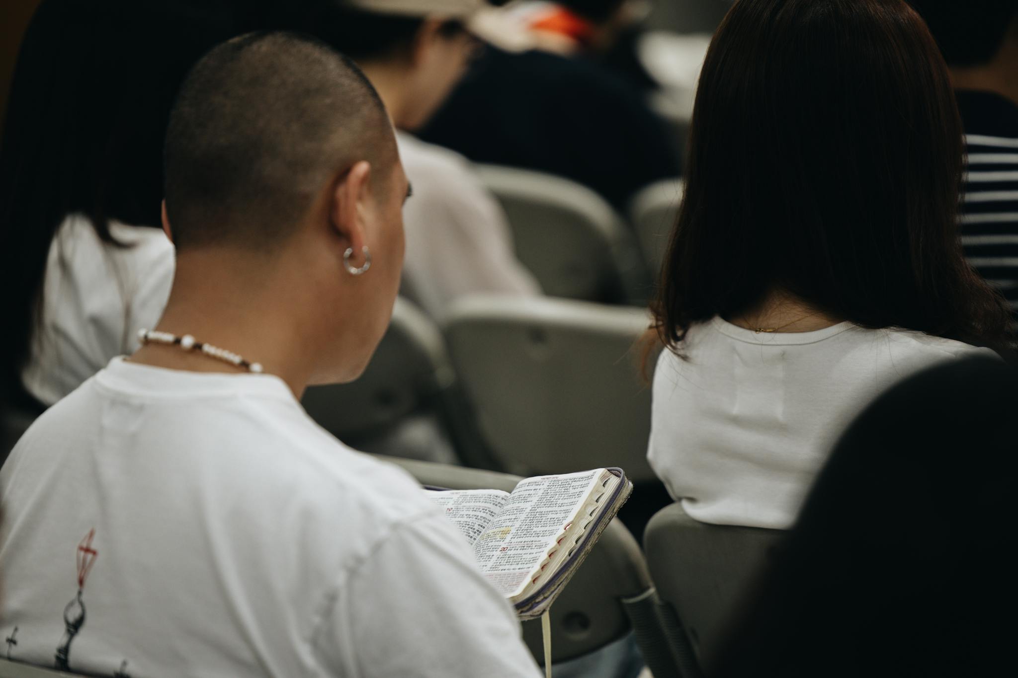 A young adult reading a Bible during a church session, reflecting faith and devotion.
